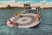 Colorized photo of people playing on a large spinning disc on the lake