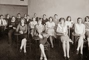 Black and white photo of young adult students seated at desks in classroom