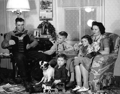 Black and white photo of family with three children and dog in living room