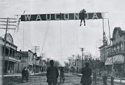 Black and white photo of people raising large banner reading "Wauconda" downtown