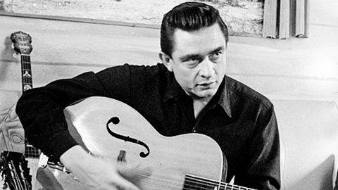 Photo of Johnny Cash holding guitar