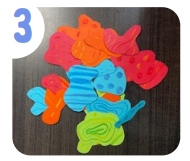 Labeled "three." A pile of colorful paper shapes decorated with various bright patterns.