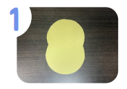 Labeled "one." A sheet of yellow paper cut to look like the outline of a chick on a brown table.