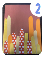 Labeled "two." Several strips of colored paper of various colors and patterns with rounded tops have been glued onto a brown sheet of construction paper.