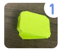 Labeled "one." A strip of green paper folded many times with the corners cut to a rounded shape. 