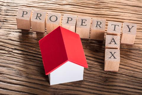 Photo of the words "property tax" and a wooden toy house