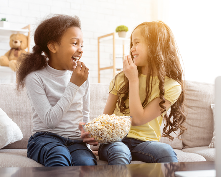 Two young girls sharing a bowl of popcorn